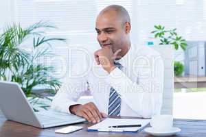 Smiling businessman looking at his laptop