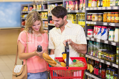 Smiling bright couple buying food porducts with shopping basket