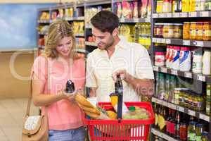 Smiling bright couple buying food porducts with shopping basket