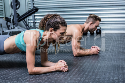 Muscular couple doing planking exercises