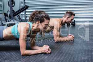 Muscular couple doing planking exercises