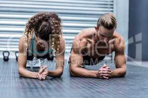 Muscular couple doing planking exercises