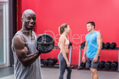 Smiling muscular man lifting a dumbbell