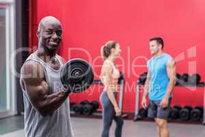 Smiling muscular man lifting a dumbbell