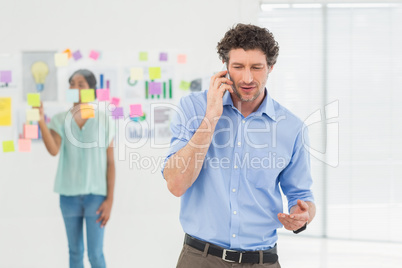 Businessman having phone call while his colleague posing