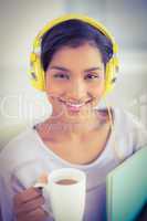 Casual businesswoman is drinking coffee while listening to music