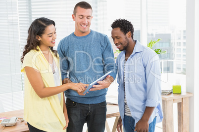 Portrait of smiling colleagues standing and using tablet compute