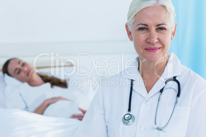 Female doctor smiling at camera while her patient sleeping