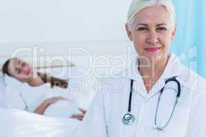 Female doctor smiling at camera while her patient sleeping