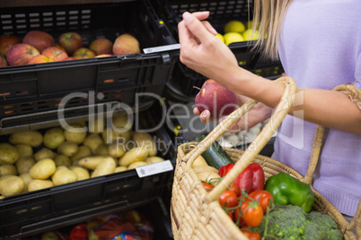 Smiling woman taking a fruit in the aisle