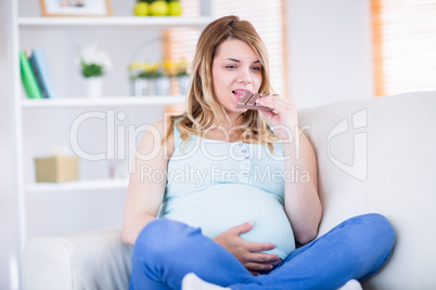 Pretty pregnant woman eating chocolate