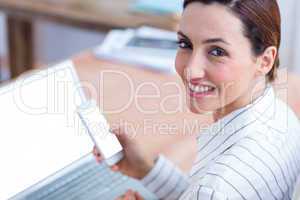 Brunette businesswoman smiling using laptop and her mobile