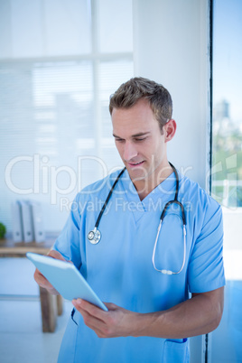 Smiling doctor watching his tablet