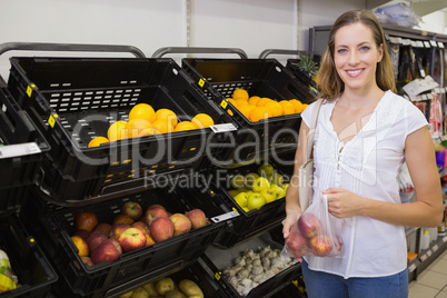 Smiling pretty blonde woman buying apples