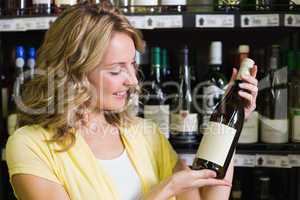 Smiling pretty blonde woman showing a wine bottle