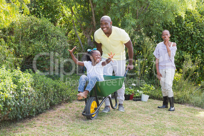 Happy smiling couple playing with wheelbarrow and their daughter Happy smiling couple playing with wheelbarrow and their daughter