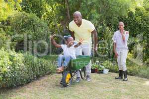 Happy smiling couple playing with wheelbarrow and their daughter