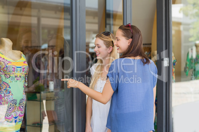 Smiling friends finger pointing a dress