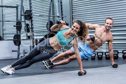 Smiling muscular couple doing side plank