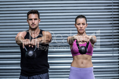 A muscular couple lifting kettlebells