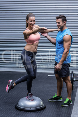 Muscular woman standing on a bosu ball