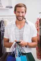 Portrait of smiling man with shopping bags using smartphone