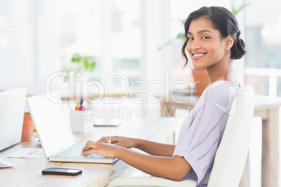 Cheerful casual businesswoman using laptop