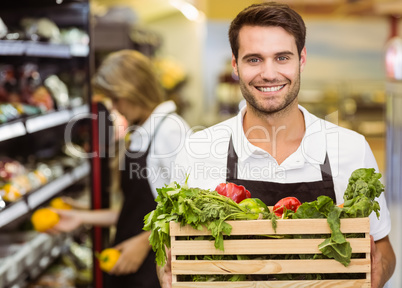 Portrait of a smiling staff man holding a box of fresh vegetable