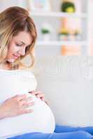 Pregnant woman touching her belly on the couch