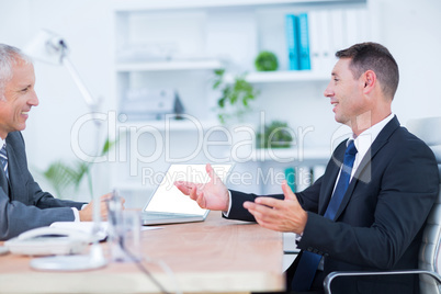 Two businessmen sitting and speaking