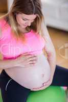 Pregnant woman touching her belly on exercise ball