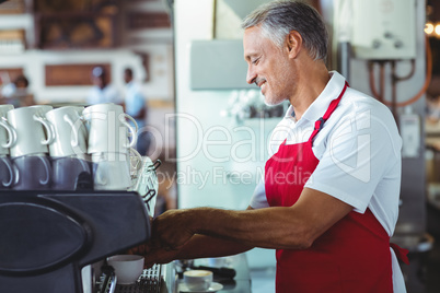 Happy barista using the coffee machine