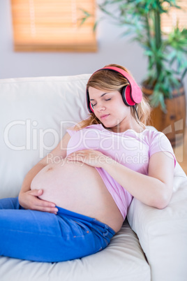 Pregnant woman listening music and touching her belly