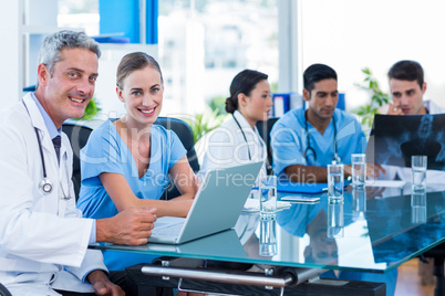 Happy doctor and nurse looking at camera while their colleagues