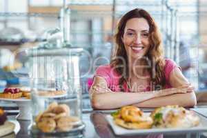 Pretty brunette smiling at camera behind counter