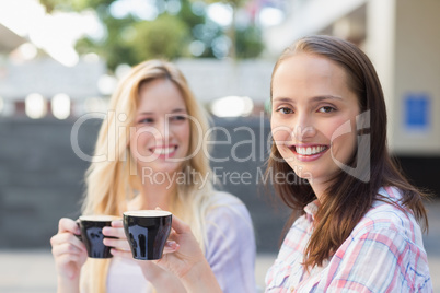 Pretty brunette smiling at camera with friend behind