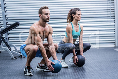 Muscular couple doing ball exercise