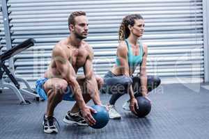 Muscular couple doing ball exercise