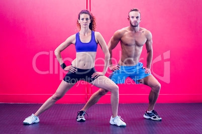 Muscular couple doing leg stretching