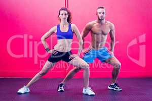 Muscular couple doing leg stretching