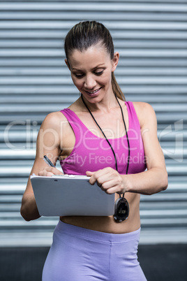 A female coach writing on her clipboard