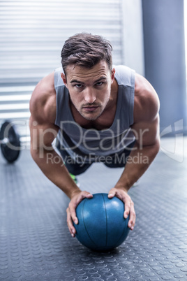 Muscular man on a plank position with a ball