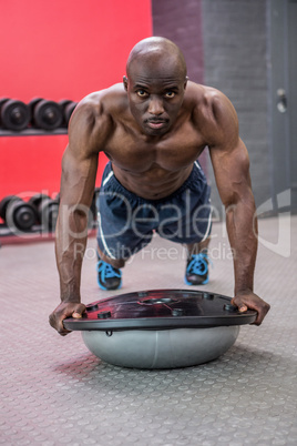 Portrait of muscular man exercising with bosu ball