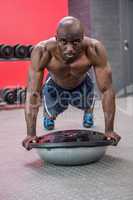 Portrait of muscular man exercising with bosu ball