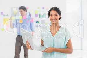 Smiling businesswoman presenting laptop screen with colleague b
