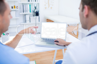 Concentrated medical colleagues working with laptop and pointing