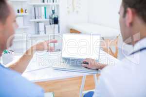 Concentrated medical colleagues working with laptop and pointing