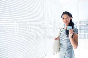 Smiling businesswoman looking at camera with credit card