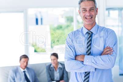 Businessman looking at camera with his colleagues behind him