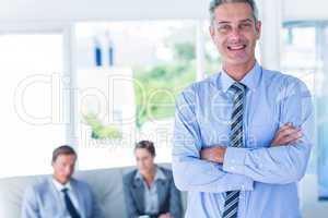 Businessman looking at camera with his colleagues behind him